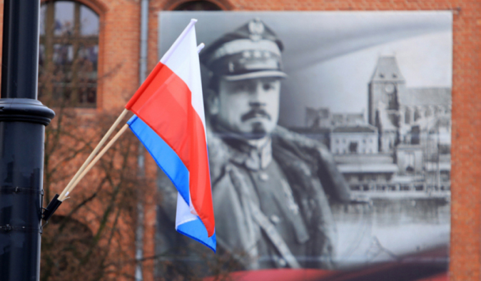 Na zdjęciu: flaga państwowa, w tle plakat z podobizną Józefa Hallera