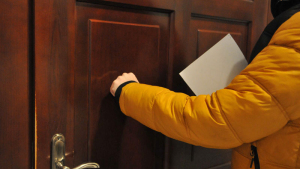 Mężczyzna w żółtej kurtce puka do drzwi