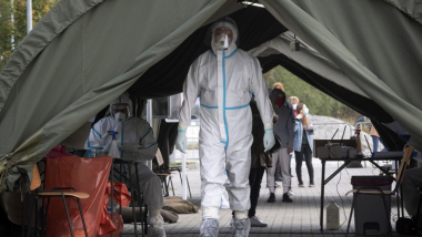Na zdjęciu widać osobę ubraną w kombinezon ochronny, pobierającą próby do testów na obwecność koronawirusa