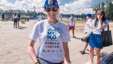 Na zdjęciu dziewczyna z koszulką Dbajmy o H2O uśmiecha się na przystani w Toruniu