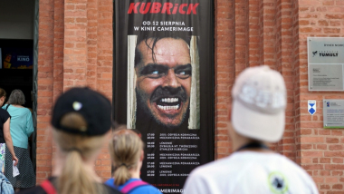Na zdjęciu osoby wchodzą do kina Camerimage, na fasadzie budynku baner przeglądu z kadrem z filmu Lśnienie