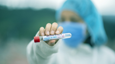 Na zdjęciu: pielęgniarka trzyma w wyciągniętej dłoni ampułkę ze szczepionką