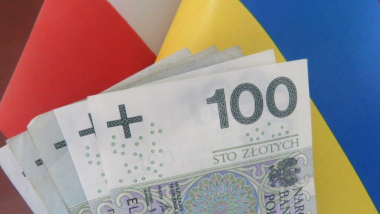 Na zdjęciu banknoty stuzłotowe w tle flaga Polski i Ukrainy