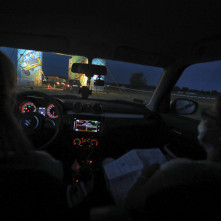Osoby w maseczkach siedzą w samochodzie, który wjeżdża na teren festiwalu Auto Skyway