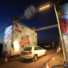 Na zdjęciu widać podświetloną bramę wjazdową na teren festiwalu Auto Skyway i samochód, który w nią wjeżdża