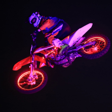 Na zdjęciu widać podświetlonego zawodnika wykonującgo motocrossowe ewolucje