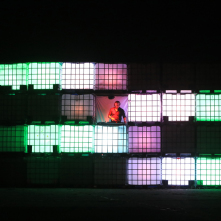 Na zdjęciu widaćinstalację złożoną z oświetlonych plastikowych pudeł, pomiędzy którymi widać mężczyznę