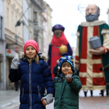 Dwoje małych dzieci stoi na ulicy Szerokiej, w tle figury trzech króli