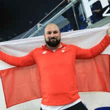 Michał Haratyk pozuje z polską flagą po zdobyciu srebrnego medalu.