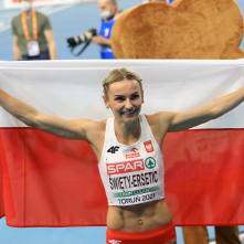 Justyna Święty-Ersetic cieszy się ze srebrnego medalu z polską flagą w rękach.