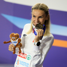 Justyna Święty-Ersetic na podium biegu na 400 metrów ze srebrnym medalem w zębach.