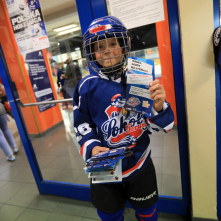 Chłopiec w stroju hokejowym reklamuje naukę jazdy na łyżwach