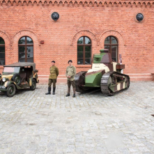 Zabytkowe pojazdy wojskowe stoją na tle Muzeum Twierdzy Toruń.