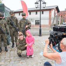 Dziewczynka pozuje z żołnierzami do zdjęcia.