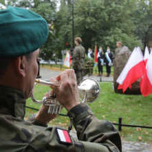 Trębacz wojskowy przy obelisku, przy którym ustawione sa flagi państwowe