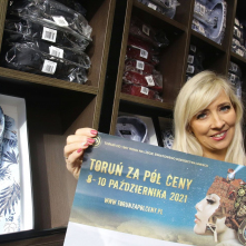 ekspedientka w sklepie z koszulami prezentuje plakat akcji