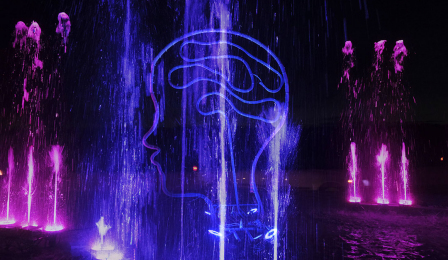 Na zdjęciu jest podświetlona fontanna i instalacja w kształcie głowy ludzkiej