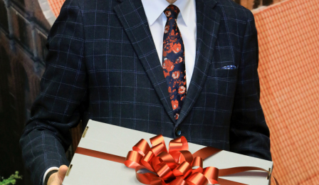 Prezydent Michał Zaleski w czapce Mikołaja trzyma pudełko z prezentem