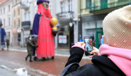 Olbrzymie figury trzech króli podążają ulicą Szeroką, na pierwszym planie osoba robiąca zdjęcie telefonem