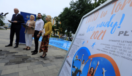 Prezydent Michał Zaleski i przedstawiciele magistratu podczas konferencji prasowej "Lato bez nudy w Toruniu" - na pierwszym planie plakat informujący o wydarzeniach w ramach akcji