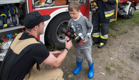 Strażak pokazuje małemu chłopcu sprzęt strażacki