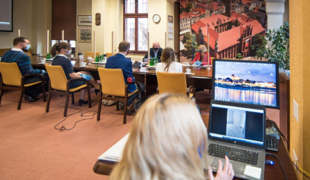 Prezydent Michał Zaleski i Elżbieta Kowalska, zastępca dyrektora Wydziału Gospodarki Nieruchomościami, siedzą przy stole, na przeciwko nich, oddzieleni plastikową ścianką siedzą absolwenci. Na pierwszym planie widać kobietę obsługująca komputer