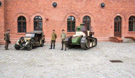 Zabytkowe pojazdy wojskowe stoją na tle Muzeum Twierdzy Toruń.