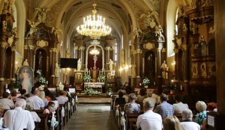 Na zdjęciu wnętrze kościoła pw. Świętych Piotra i Pawła, w ławkach siedzą wierni, widać ołtarz główny