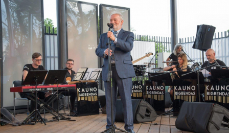 Organizator, Henryk Giza, otwiera koncert, w tle siedzą muzycy